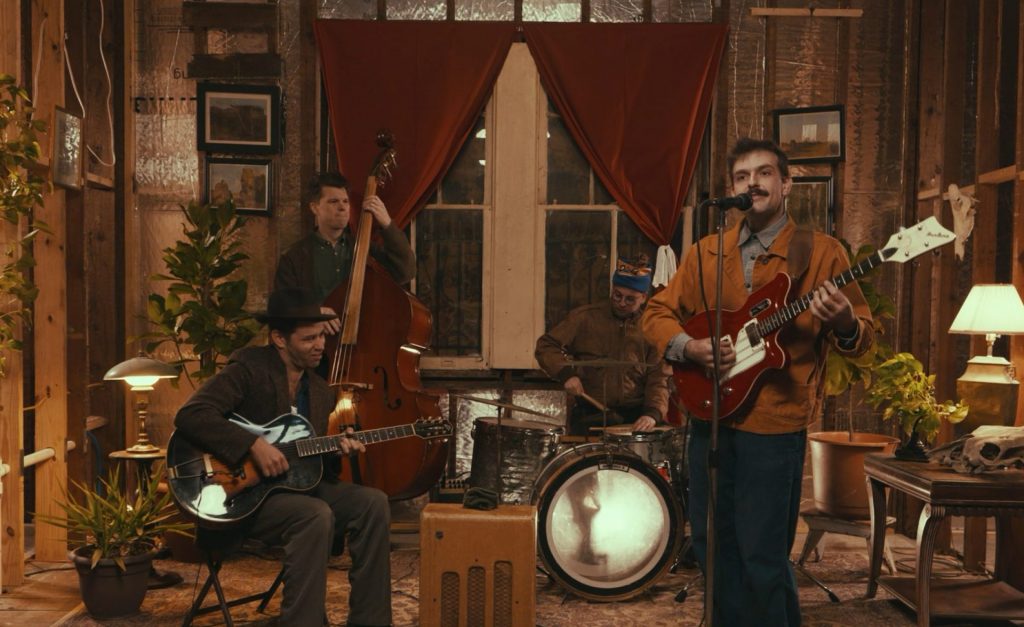 James McClaskey and the Rhythm Band performing in a warmly lit room.