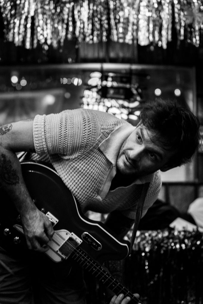 Black-and-white portrait of James McClaskey playing guitar.